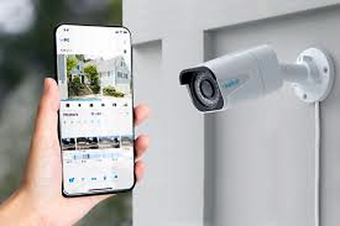 Phone showing security camera live view beside an outdoor camera